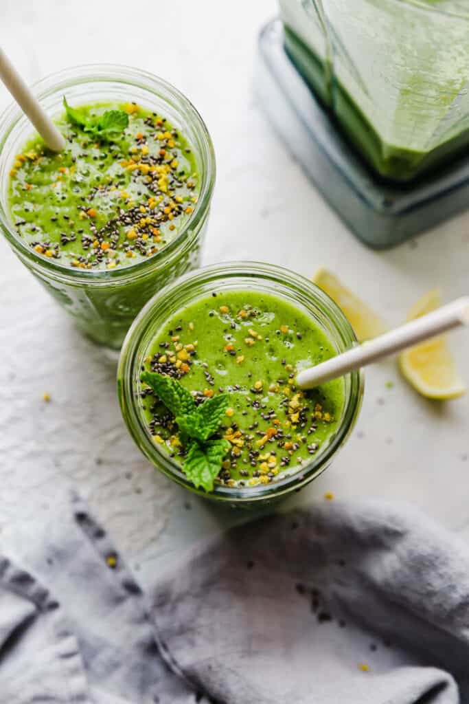 two glasses of green smoothie with straws