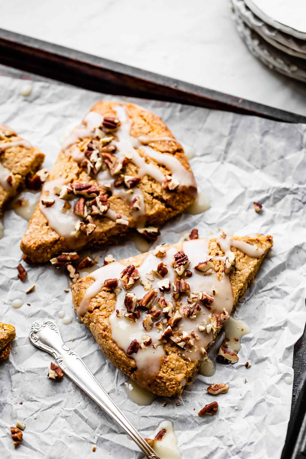pumpkin scones laid out on a parchment baking sheet with pecans