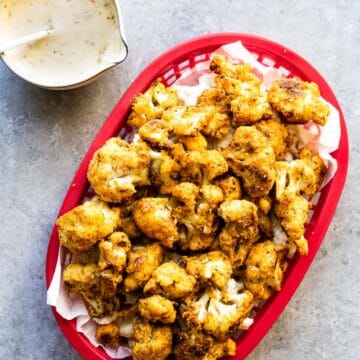 cauliflower nuggets in a red fry train with dipping sauce on the side