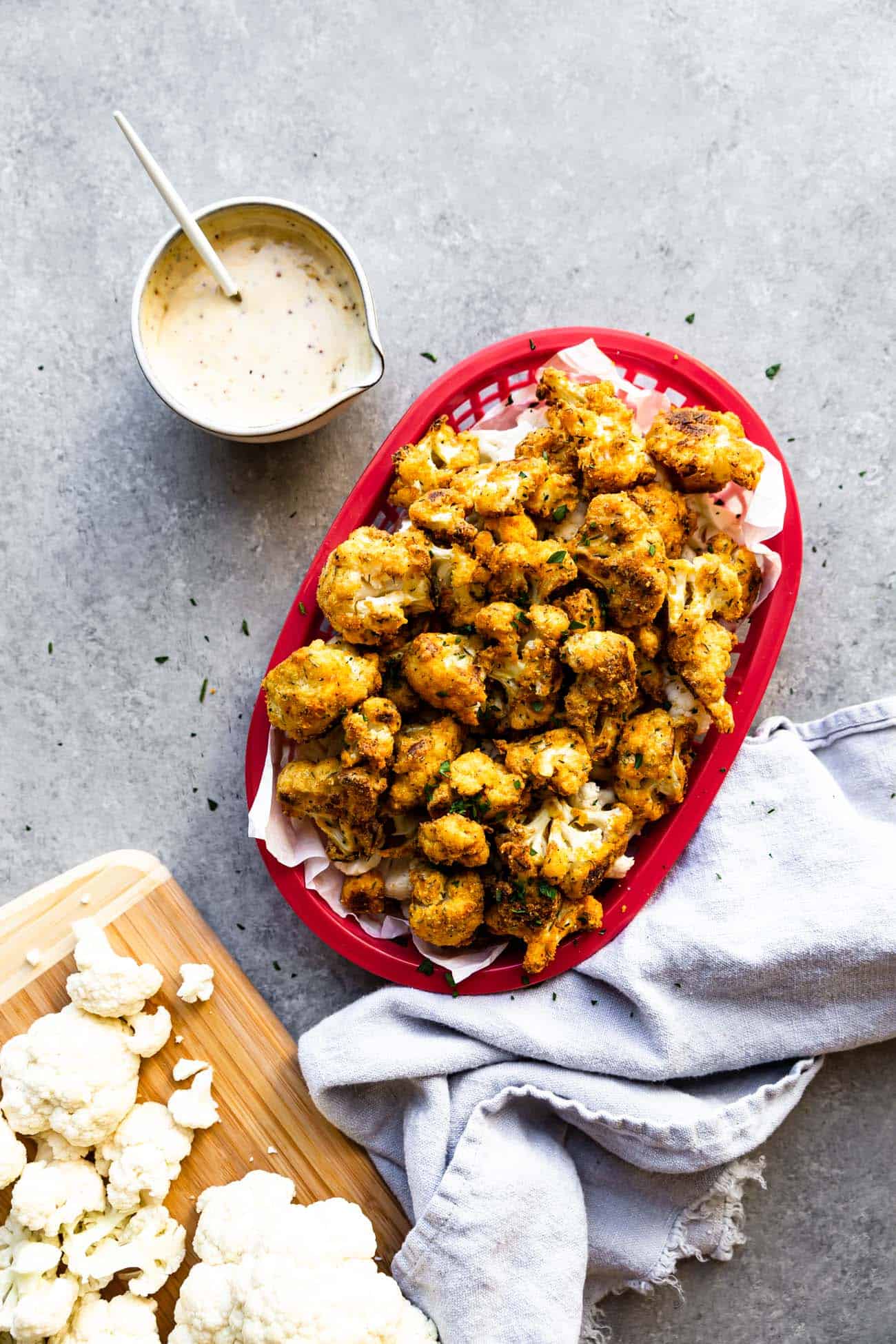 cauliflower nuggets in a red tray with cauliflower florets and sauce on the side