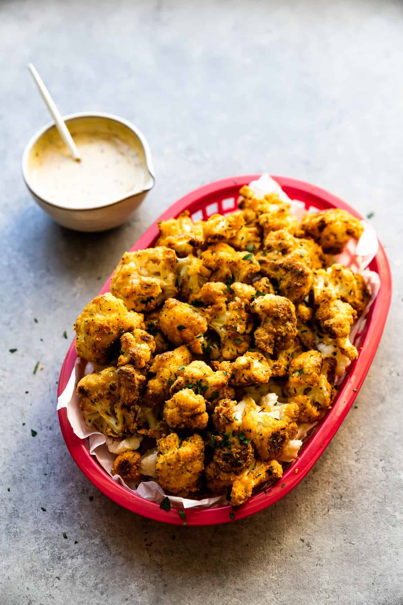 cauliflower nuggets in a red tray with honey mustard sauce on the side