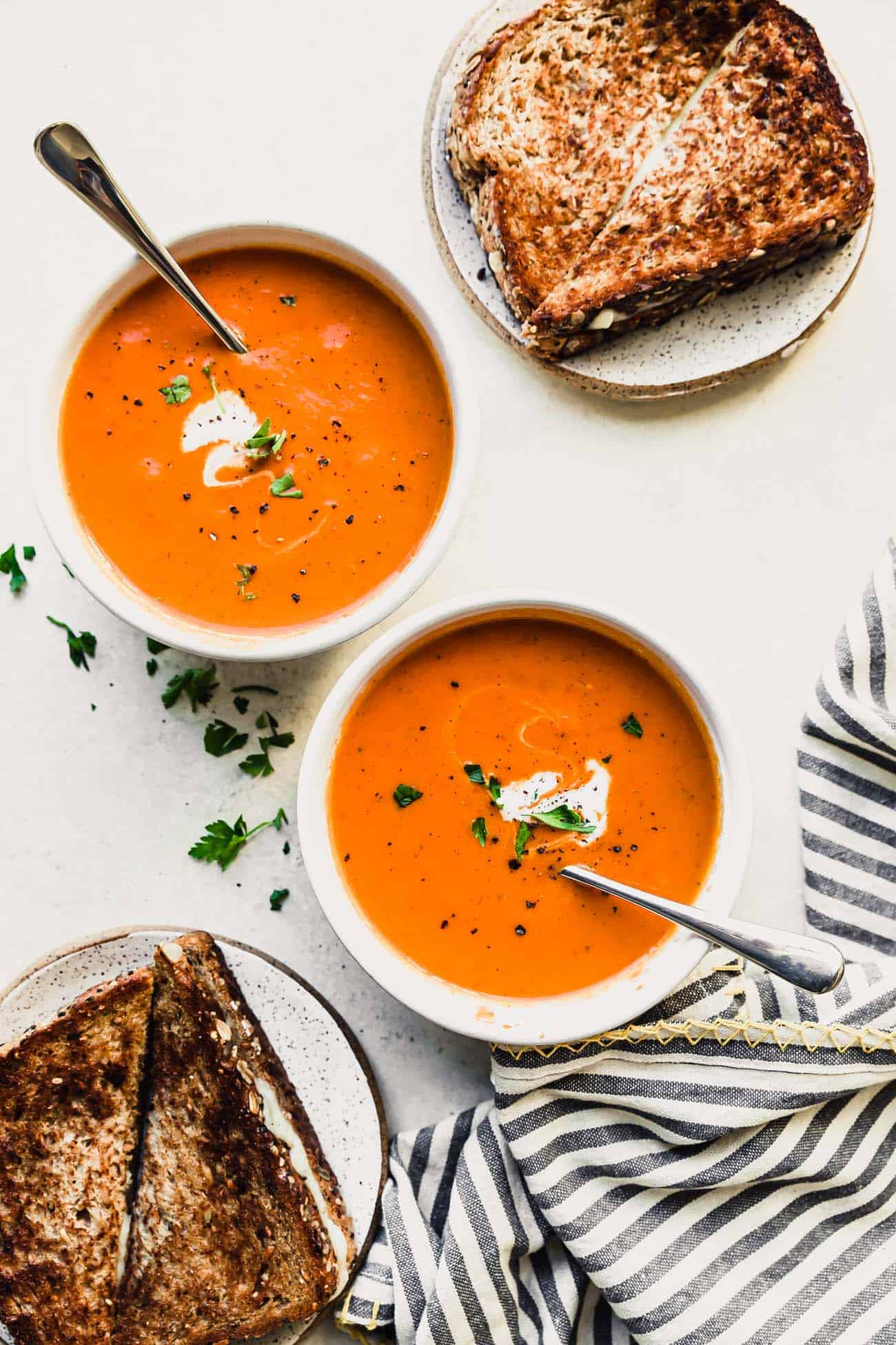 two bowls of tomato soup with grilled cheese on the side
