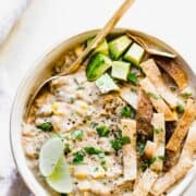 bowl of white chicken chili with a golden spoon and toppings