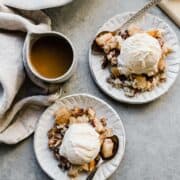 two plates of pear crisp with vanilla ice cream on top