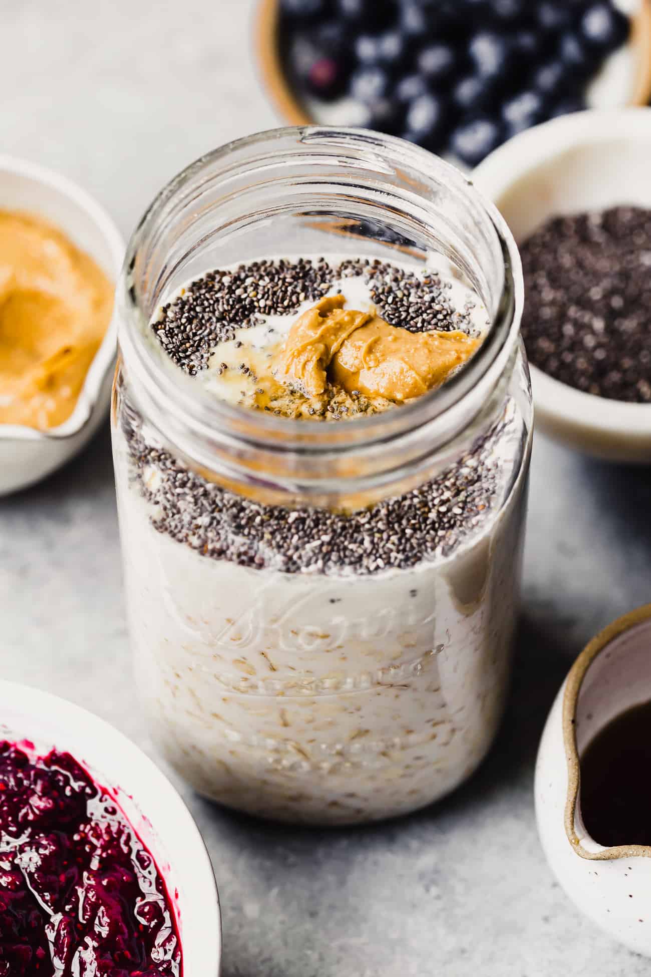 overnight oats being made in a large glass jar with peanut butter