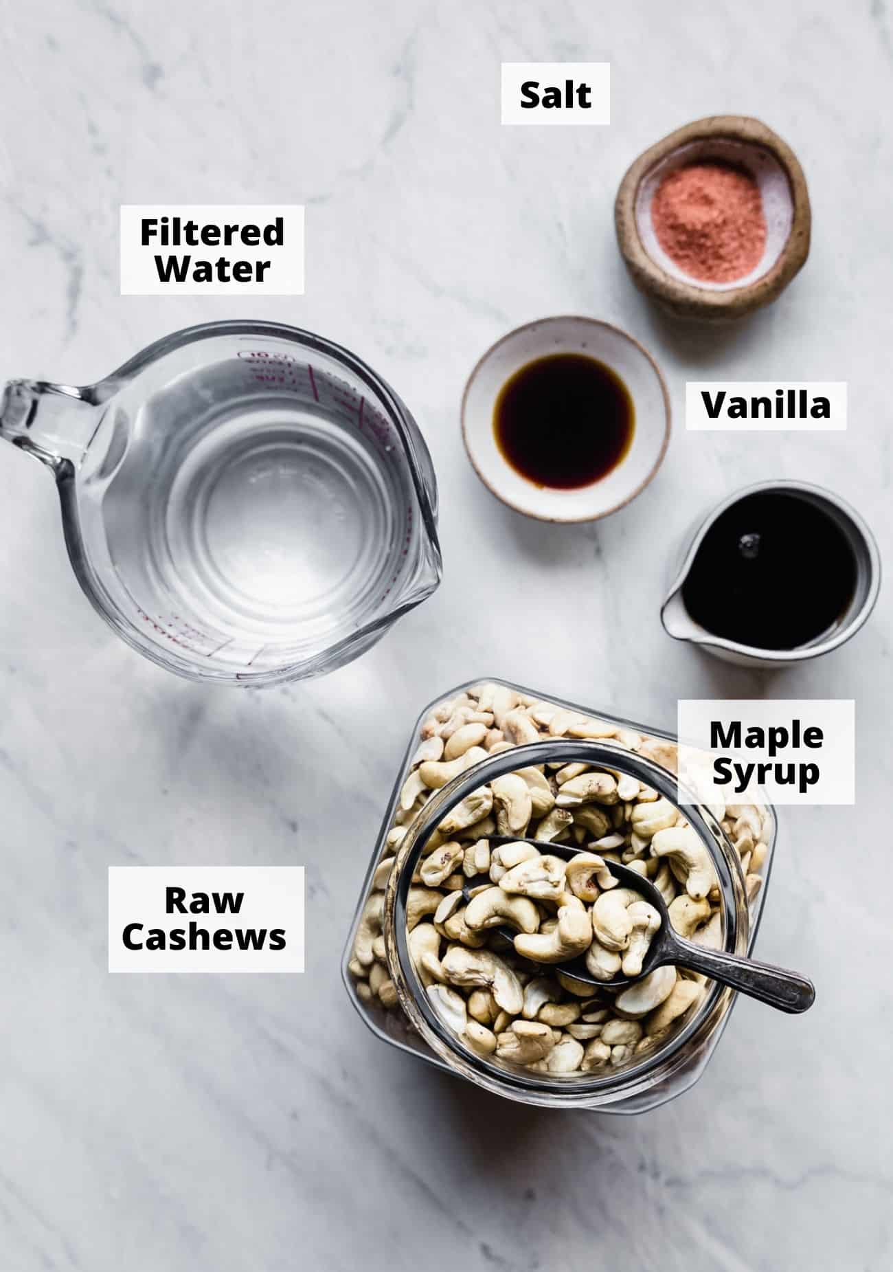 ingredients laid out to make vegan cashew creamer: Salt, Filtered Water, Vanilla, Maple Syrup, Raw Cashews