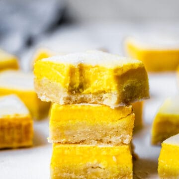 stack of lemon bars on a marble board with a bite taken out