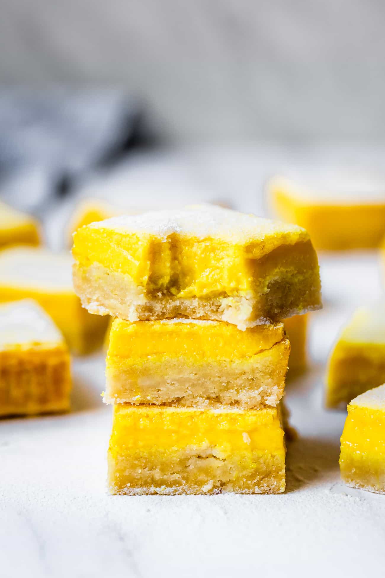 stack of lemon bars on a marble board with a bite taken out