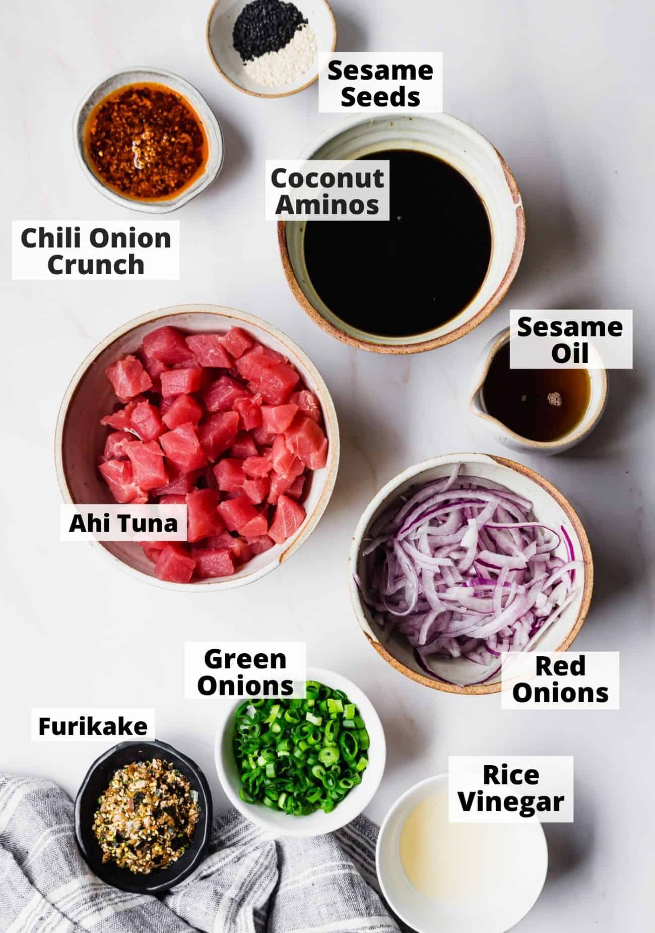 ingredients prepped and laid out for poke bowls: Sesame Seeds, Coconut Aminos, Chili Onion Crunch, Ahi Tuna, Sesame Oil, Green Onions, Red Onions, Rice Vinegar, Furikake