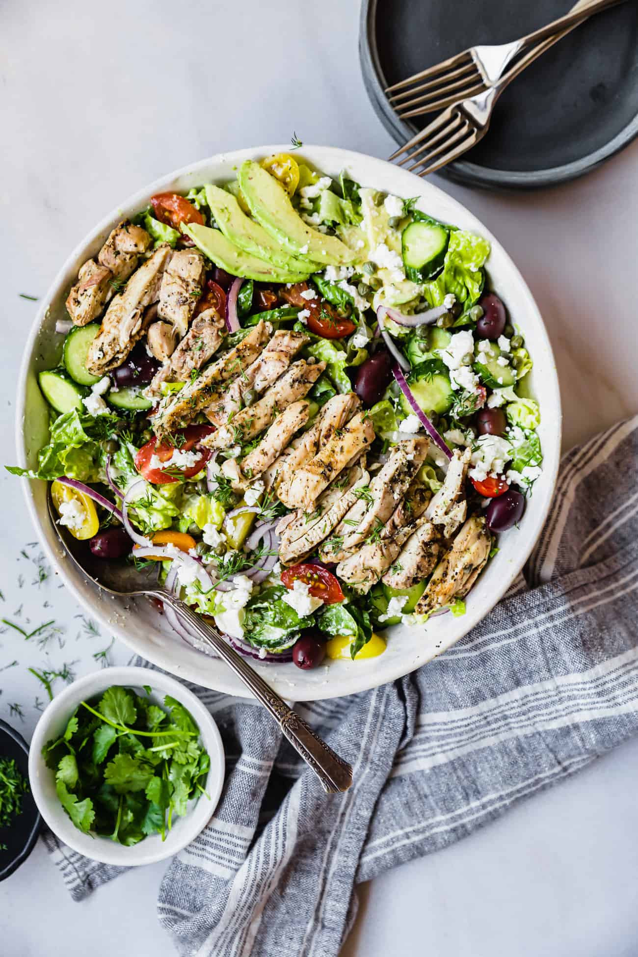 Healthy chicken salad with avocado on top and greens