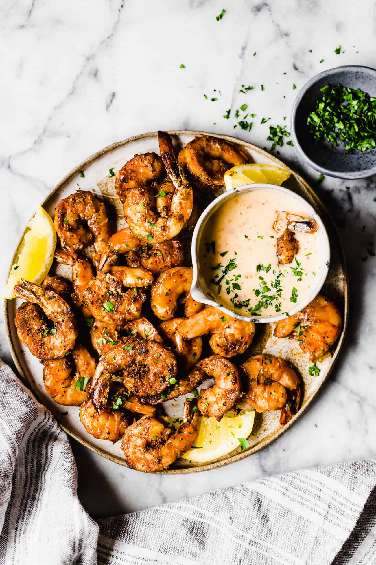 grilled blackened shrimp on a plate with fresh lemon and dipping sauce on a plate