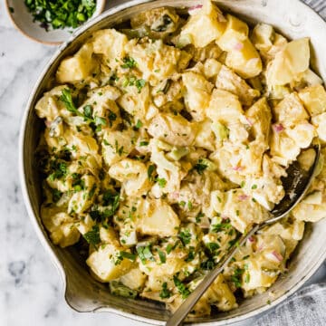 creamy instant pot potato salad in a large bowl with parsley and a spoon inside
