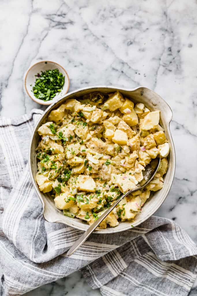 potato salad in a large ceramic bowl with fresh parsley on the side
