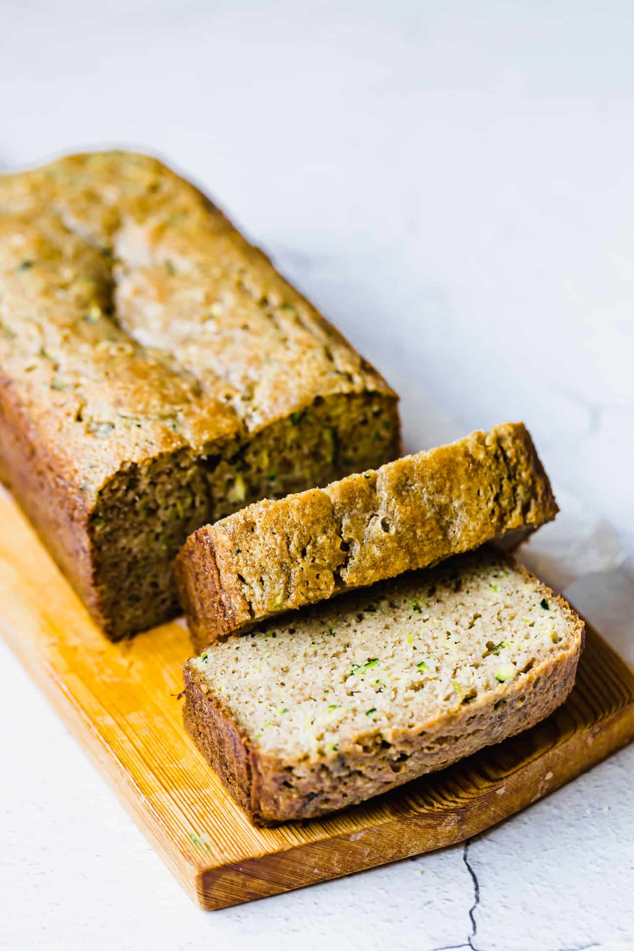 zucchini bread slices on a brown wooden cutting board