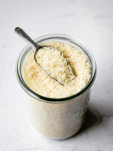 jasmine rice with a metal scoop in a glass jar