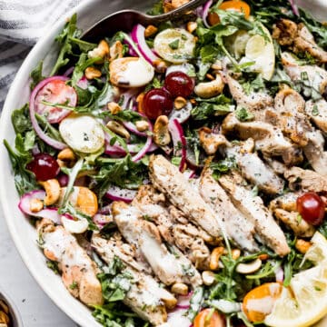arugula and chicken salad in a large bowl with a spoon