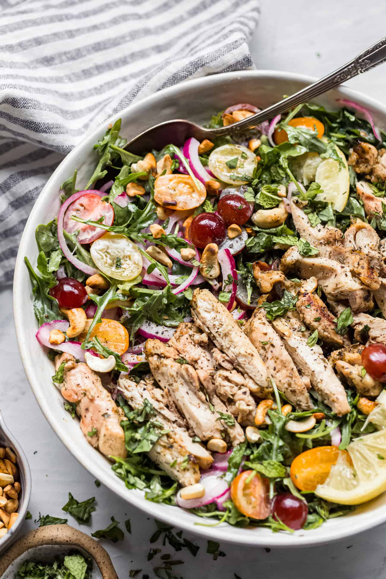 arugula and chicken salad in a large serving bowl with a spoon
