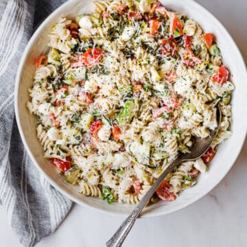 gluten free pasta salad with a large spoon in a white ceramic bowl