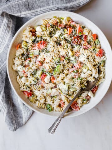 gluten free pasta salad with a large spoon in a white ceramic bowl