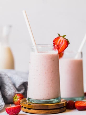 strawberry banana smoothie in a glass cup with a straw