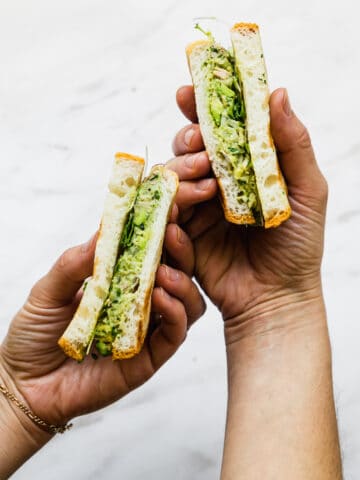 avocado and tuna salad in a sandwich being held