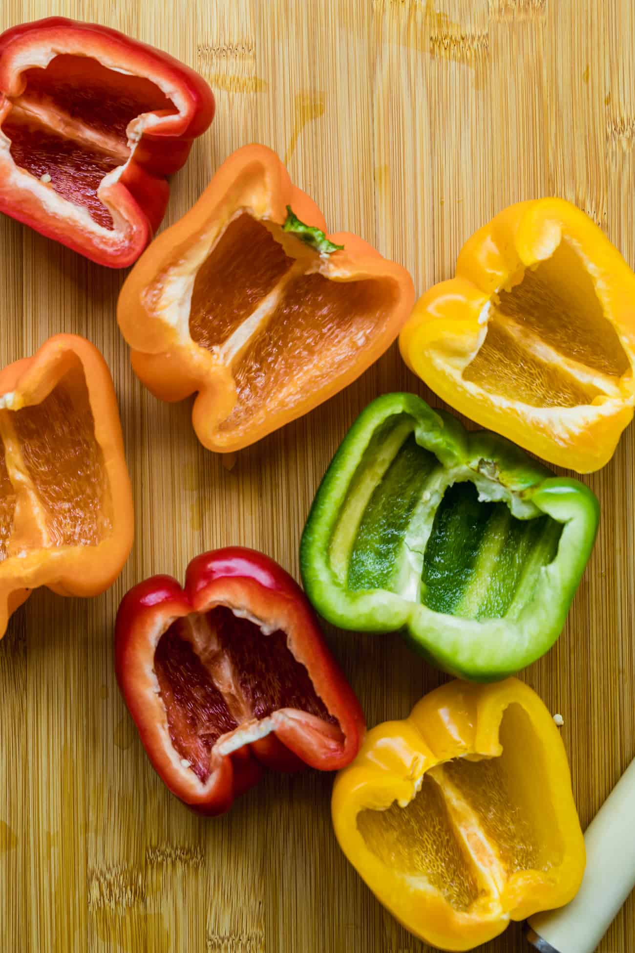 halved bell peppers on a wooden cutting board