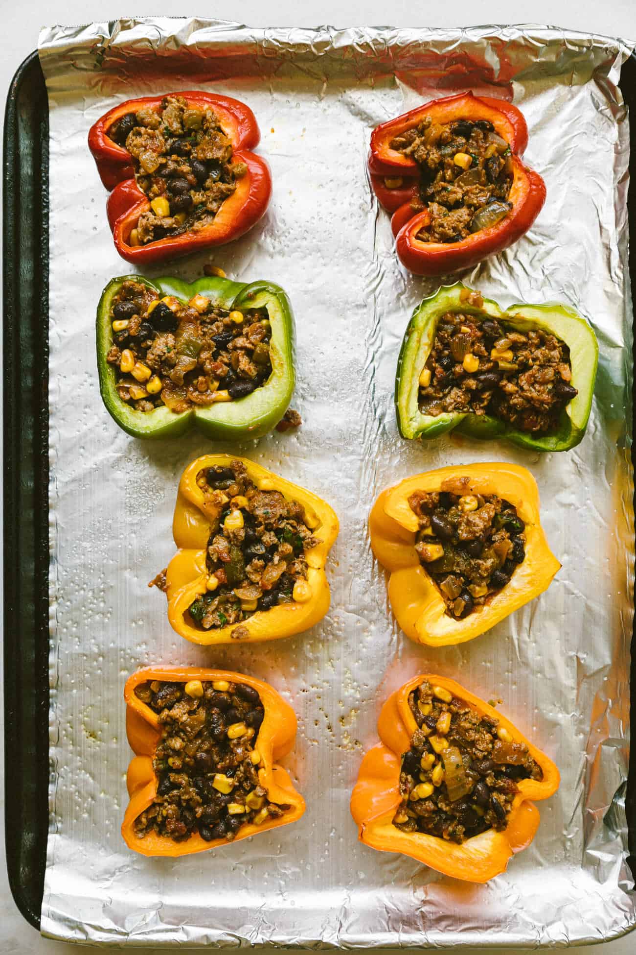 stuffed peppers on a foil lined baking sheet
