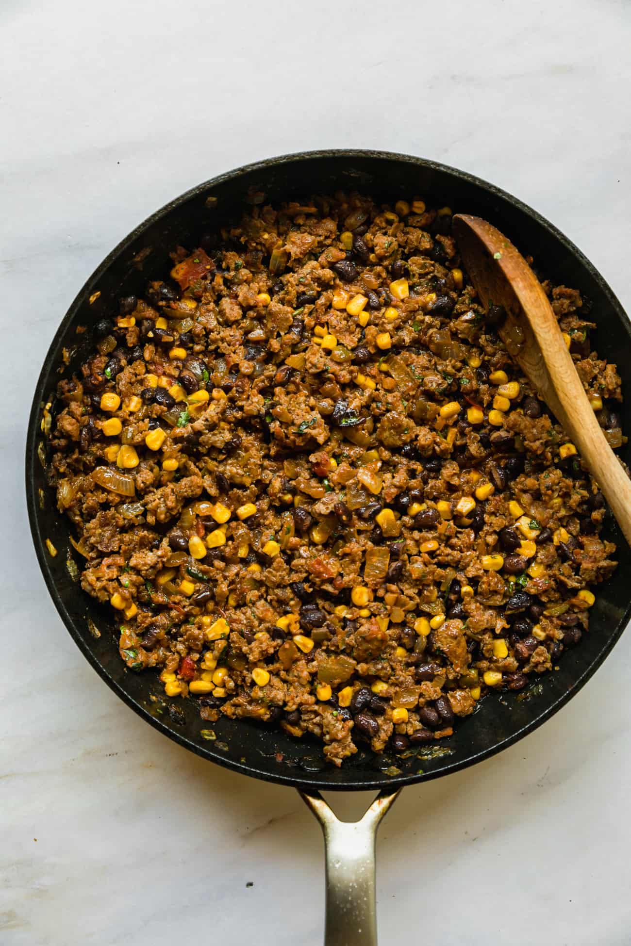 taco stuffing in a frying pan with a wooden spoon