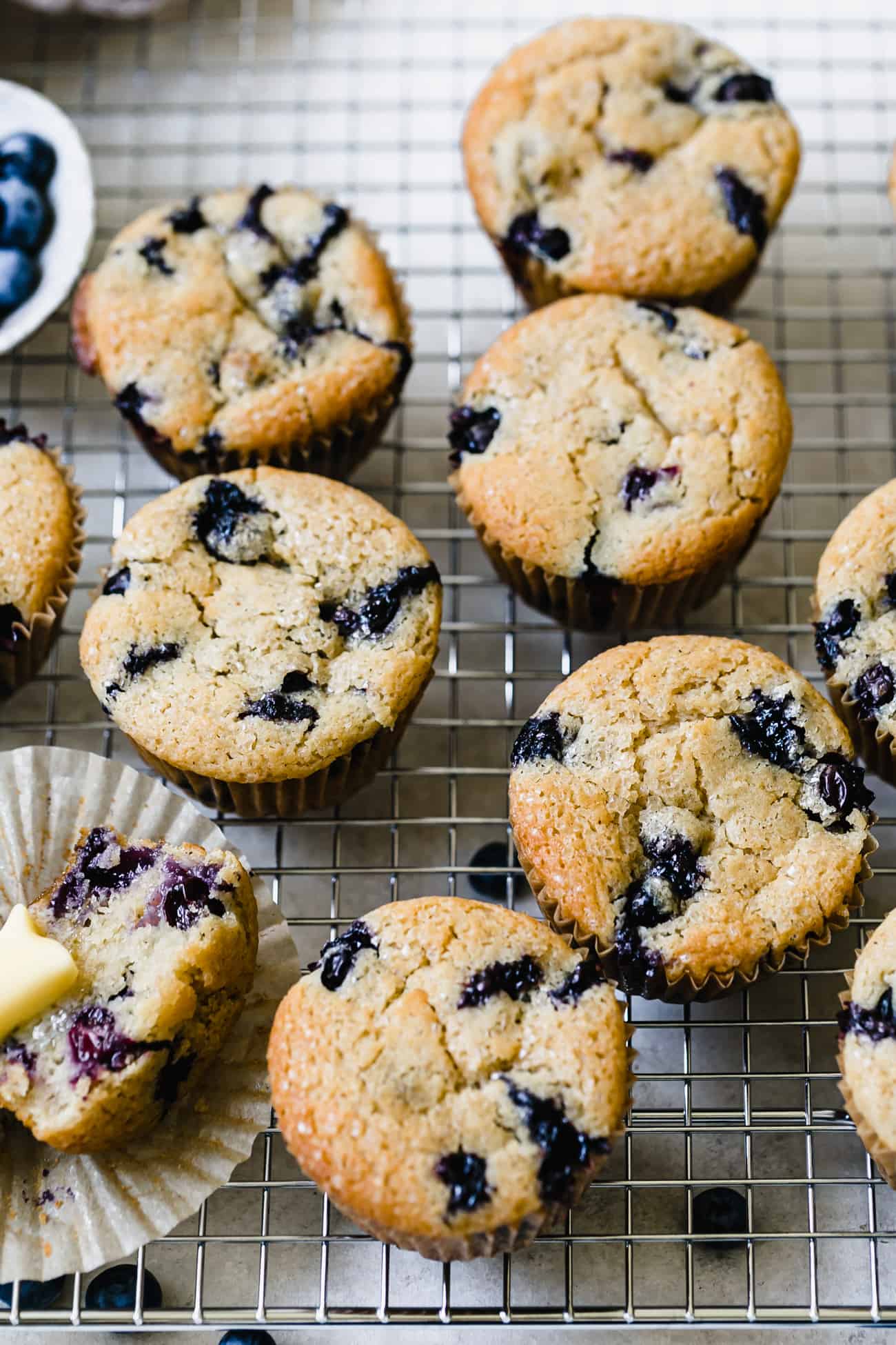 gluten free blueberry muffins on a wire rack with blueberries on top