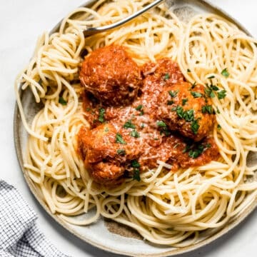 turkey meatballs on a plate with bucatini pasta and a fork