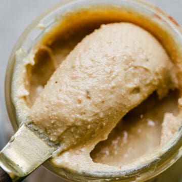 cashew butter being scooped out of a jar
