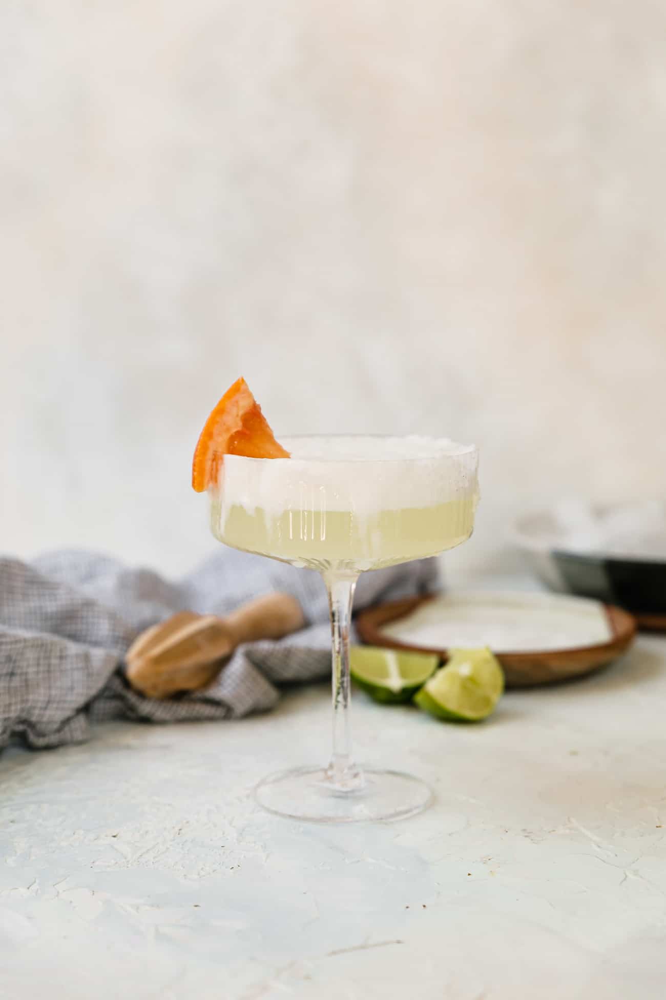 a frothy grapefruit Paloma in a coupe glass with a grapefruit garnish