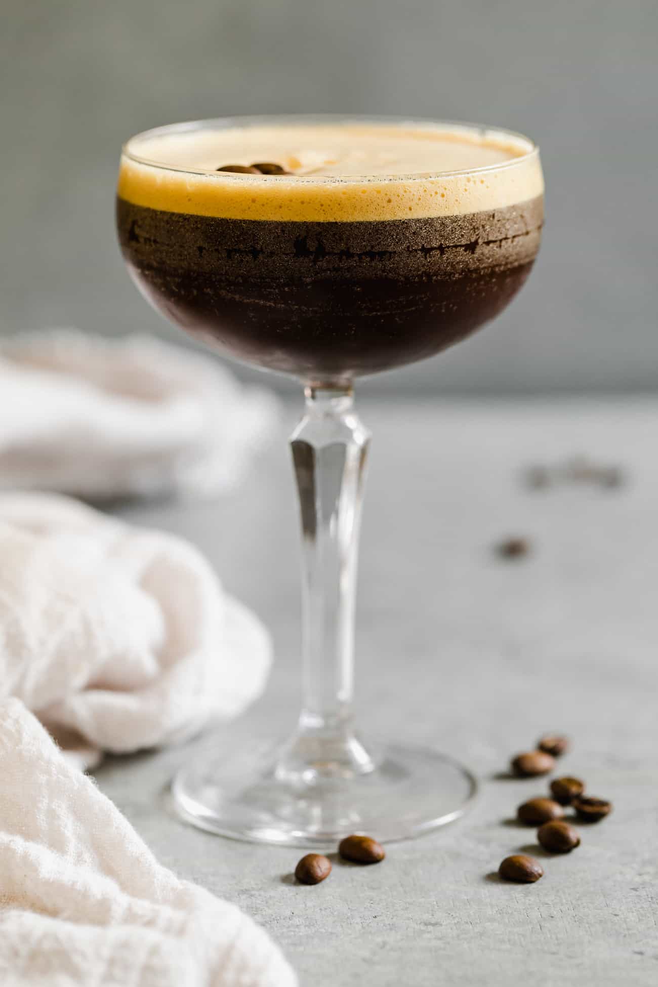 an espresso martini in a glass with espresso beans on top