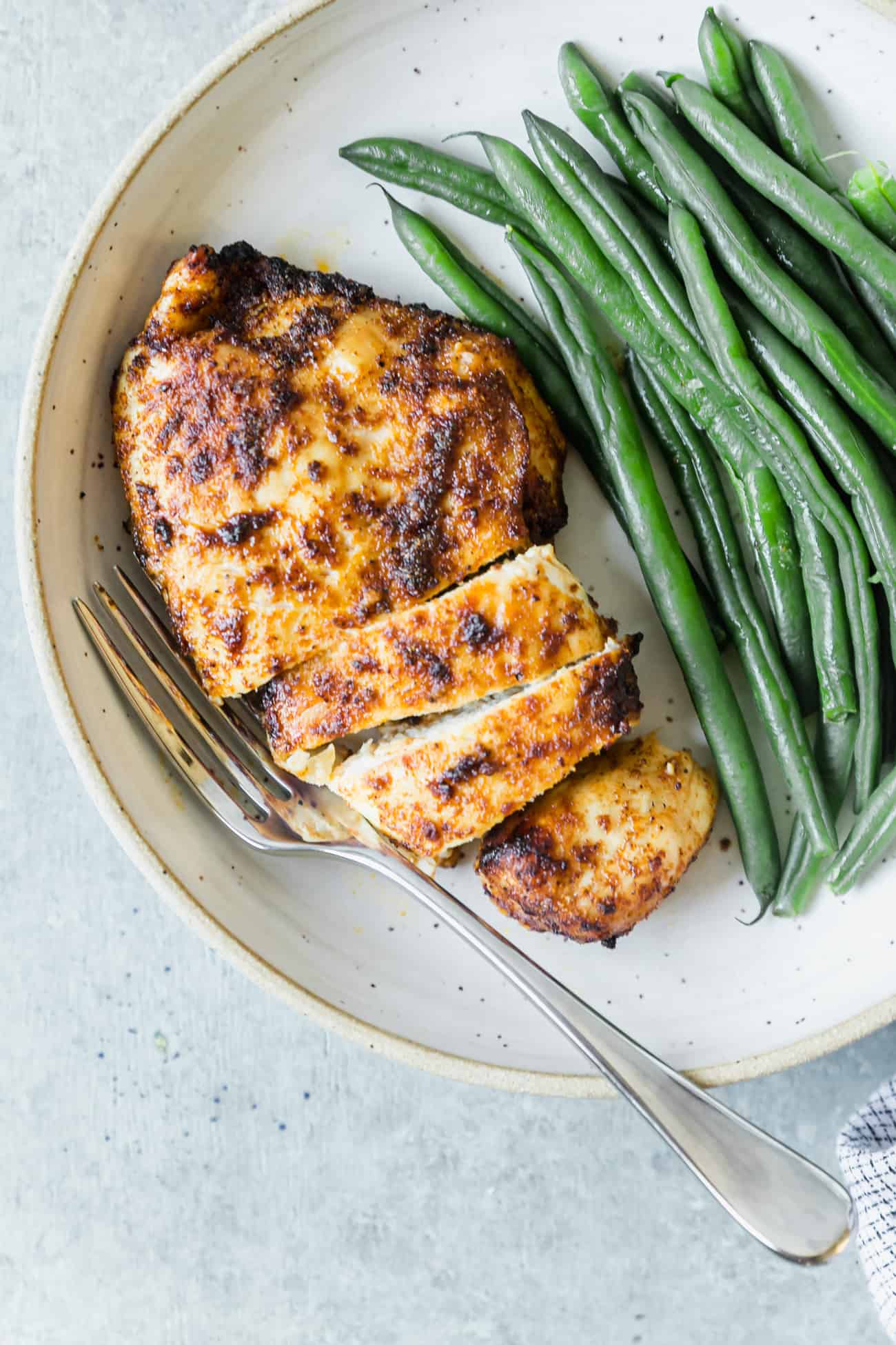 cut up air fryer chicken breast on a plate with cooked green beans