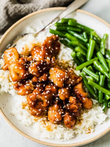honey butter chicken with green beans and white rice on a plate with a fork