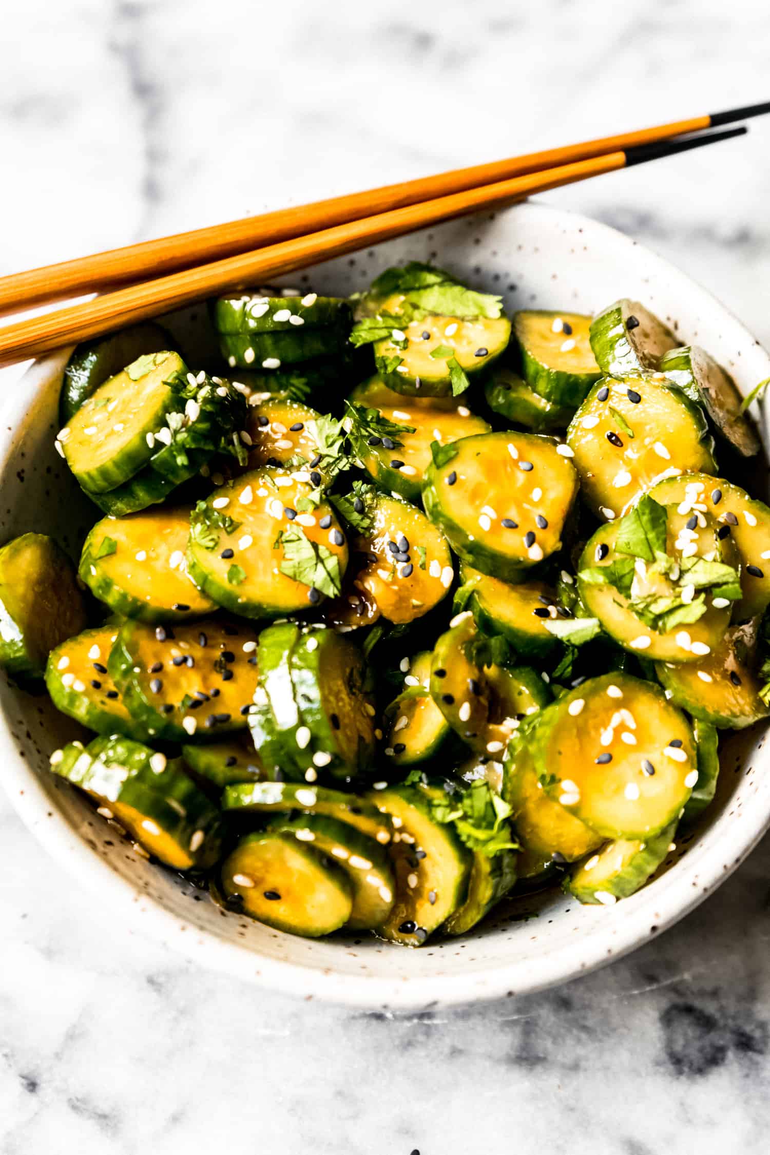 spicy cucumber salad in a bowl with brown chopsticks
